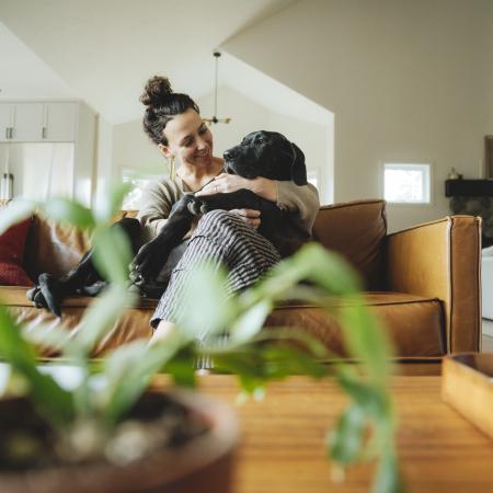 Women cuddling dog on orange couch.