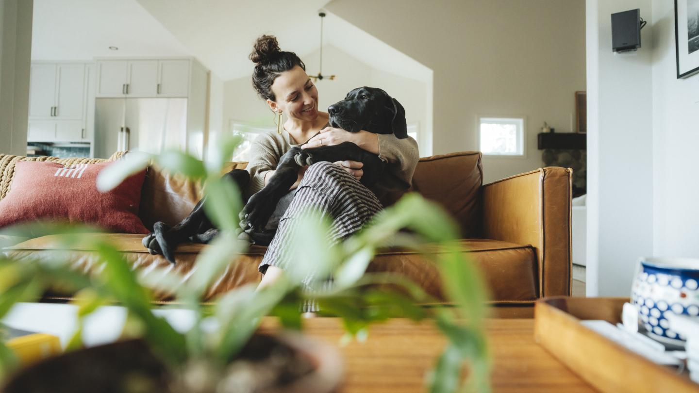Women cuddling dog on orange couch.